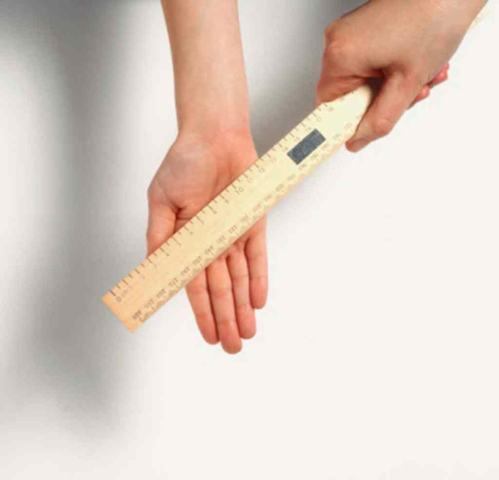 Image shows a hand extended with a ruler laying across the open palm